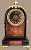 Black Belgian limestone with gilt filled decoratively incised rouge marble front panels and dial centre.Cast brass “hairy paw” feet, lion head/ring side handles and cresting.